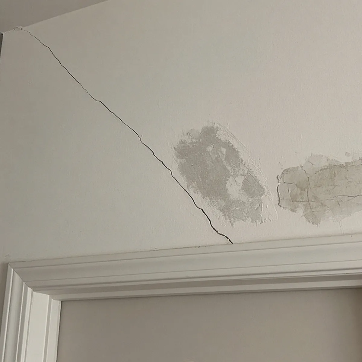 Diagonal drywall crack above an interior door